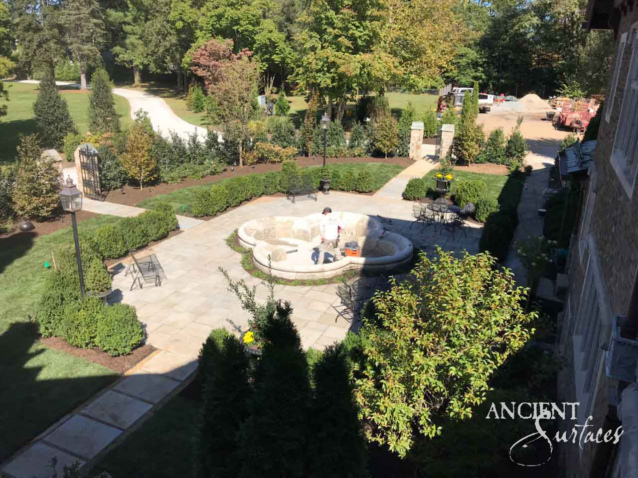 Reclaimed limestone pool fountain with a curved serpentine pool wall being set into a bluestone estate terrace surrounded by clipped hedging