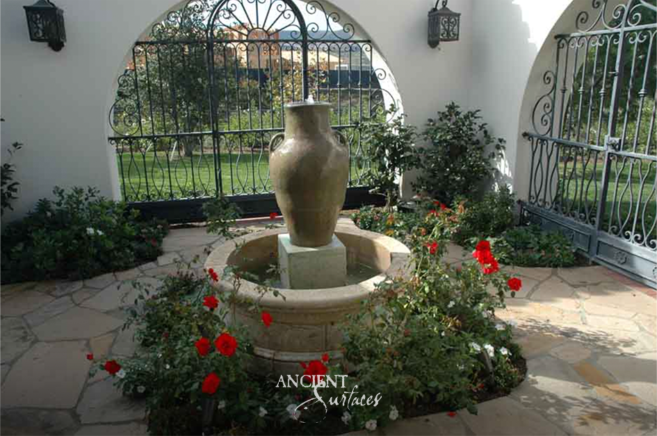 Reclaimed limestone pool fountain with a large ovoid stone urn on a plinth spilling water into a round coursed limestone pool