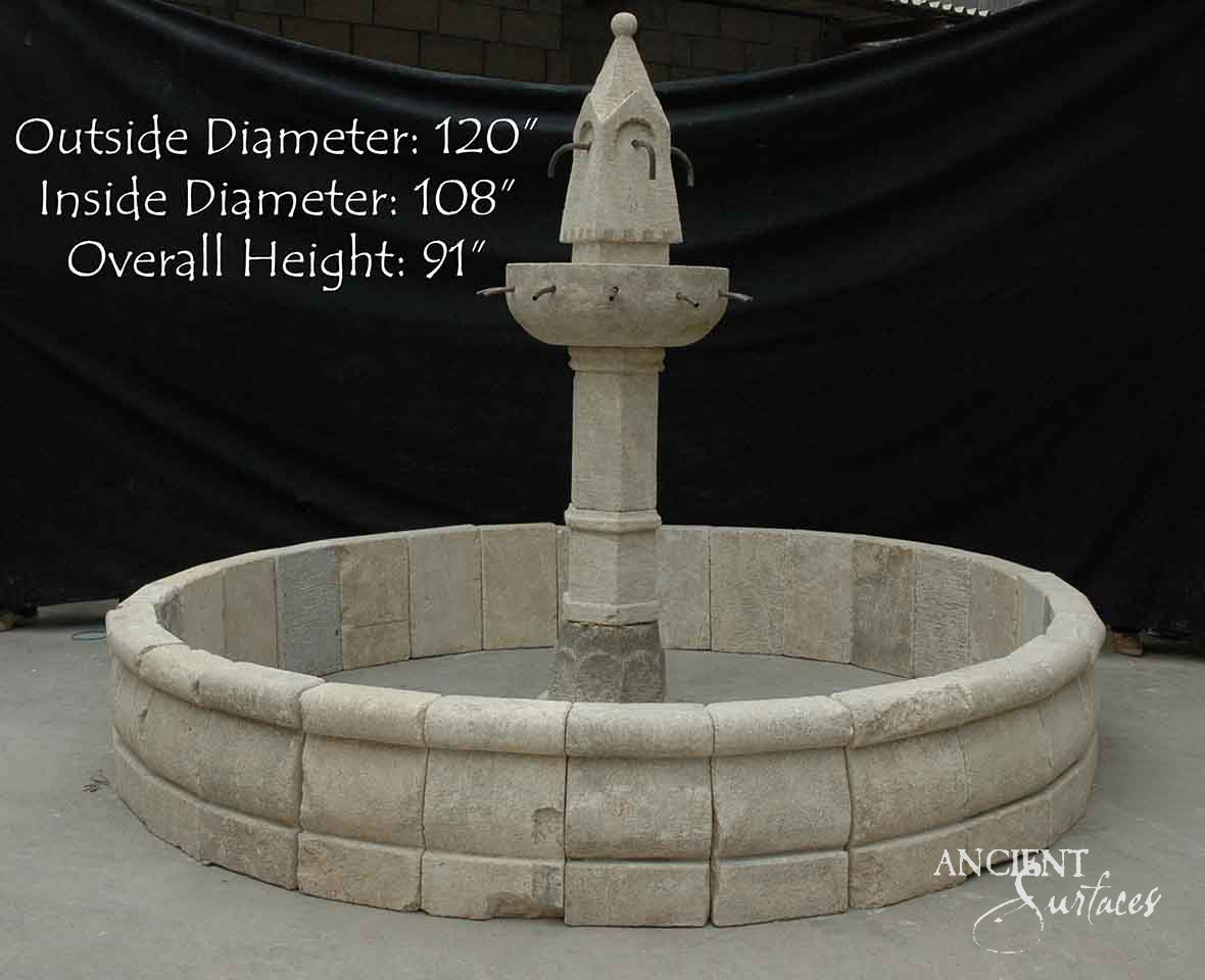 Tall reclaimed limestone pool fountain with a conical spired top, two rings of iron spouts and a round pool built from squared limestone blocks