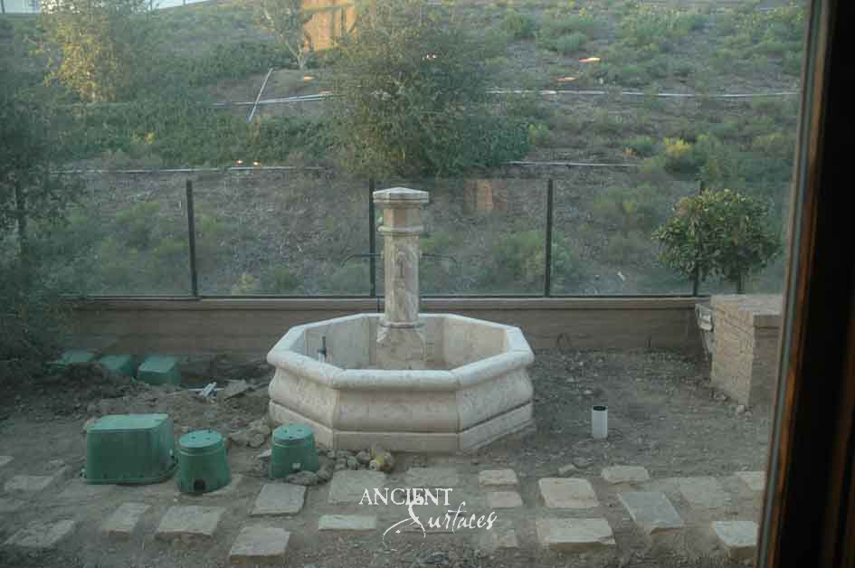 Octagonal reclaimed limestone pool fountain with a slender pillar and iron spouts newly set on a hillside terrace
